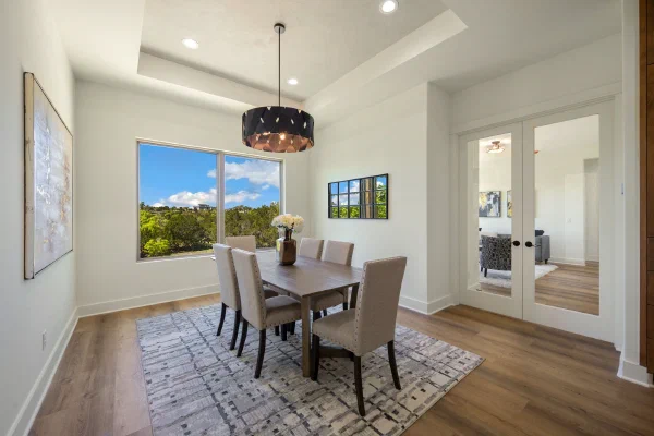 Dining room with tray ceiling, black drum chandelier, and a picture window framing Texas Hill Country views