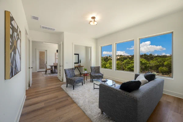 Sitting room with oversized picture windows, charcoal sofa, and French doors opening to the entry hall
