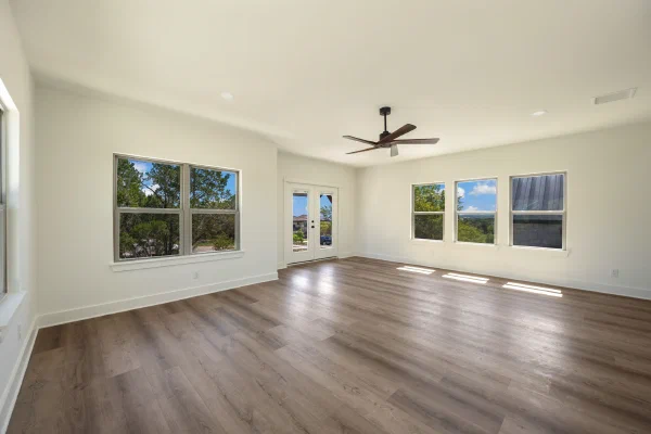 Unfurnished bonus room in a new custom home with French doors to a balcony and banks of bright windows