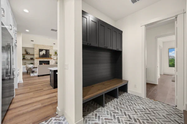 Custom home mudroom with black built-in lockers, oak bench, shiplap backing, and herringbone brick floor