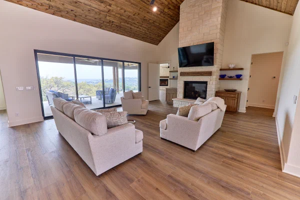 Living area with vaulted wood ceiling and glass sliders framing a covered porch and distant hills