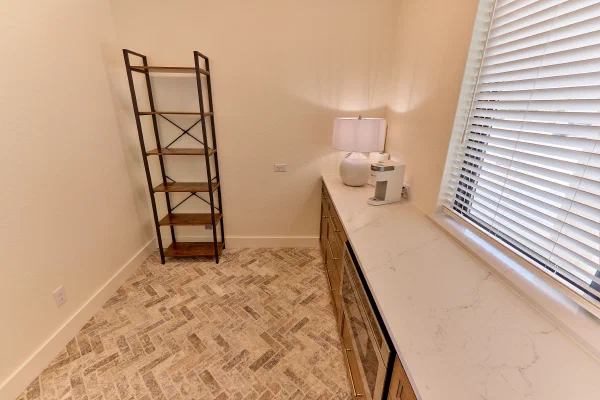 Marbled quartz counter, glass-front beverage cooler, and herringbone tile floor in a walk-in pantry