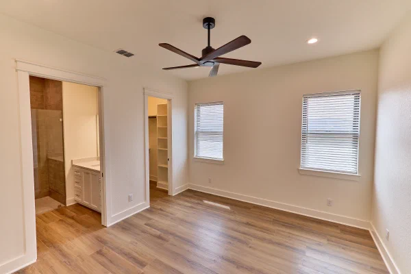 Bedroom with walnut ceiling fan, ensuite bath with tiled walk-in shower, and closet with built-in shelving