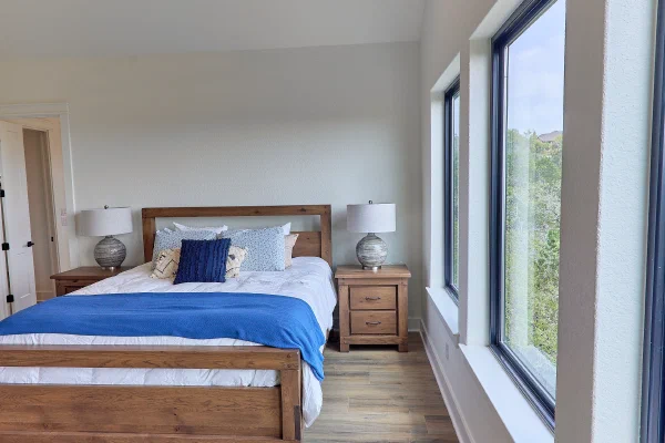 Down-rod ceiling fan hangs from a beamed cathedral ceiling above a rustic oak bed and matching nightstands