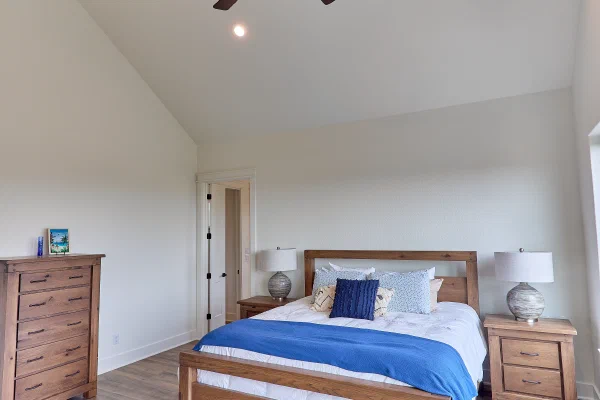 Bedroom corner with private patio door, oak dresser with mirror, and picture windows over the hillside