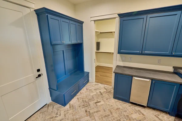 Mudroom with blue built-in bench and lockers, beverage fridge cabinet, walk-in closet, and herringbone tile floor