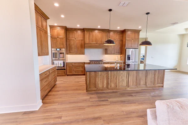 Custom home kitchen with rich oak cabinetry, an oversized black granite island and stainless double wall ovens