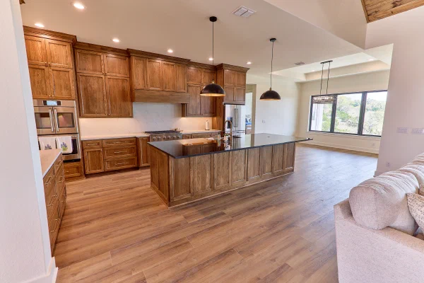 Oak cabinetry with wood vent hood, marble-look slab backsplash and a large island topped in polished black granite