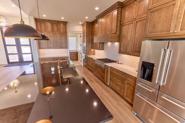 Elevated view of oak cabinetry and a black granite island with stainless sink and French-door refrigerator
