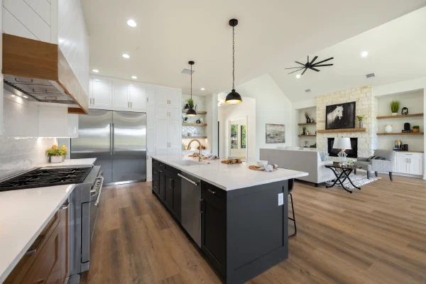 Chef's kitchen with stainless double refrigerator, pro-style gas range, black island and white quartz countertops