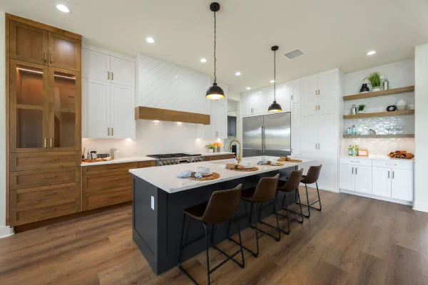 White and stained wood cabinetry with chevron shiplap hood, black island seating four and a floating-shelf beverage bar