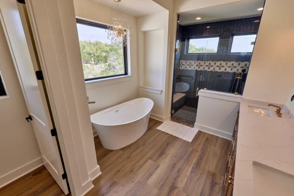 Spa-style primary bath with oval soaking tub, sputnik chandelier, and dark herringbone tile walk-in shower